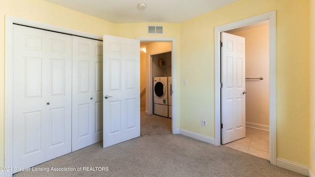 unfurnished bedroom with light carpet, a closet, and washer and clothes dryer