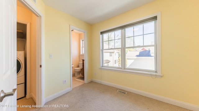 unfurnished bedroom featuring light carpet and ensuite bath