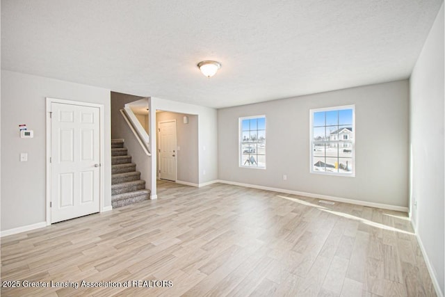 spare room with a textured ceiling and light wood-type flooring