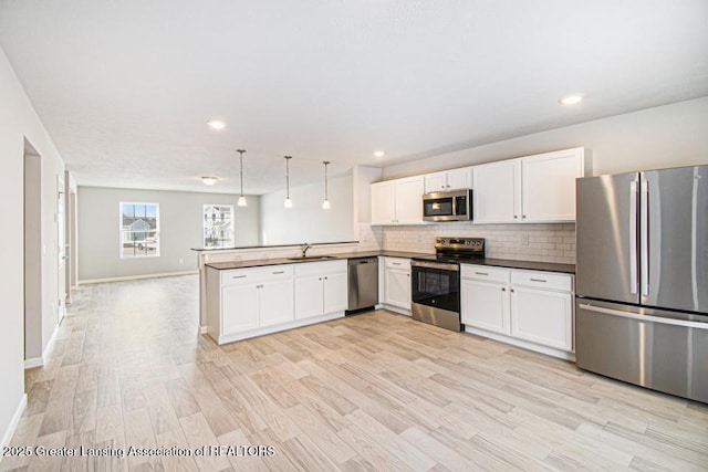 kitchen featuring appliances with stainless steel finishes, sink, white cabinets, hanging light fixtures, and kitchen peninsula