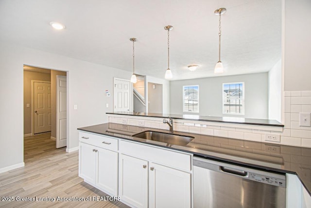 kitchen featuring sink, white cabinetry, decorative light fixtures, stainless steel dishwasher, and light hardwood / wood-style floors