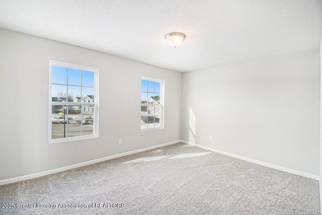 carpeted empty room with a textured ceiling