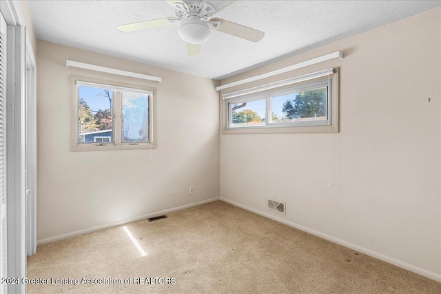 carpeted empty room featuring ceiling fan and a textured ceiling