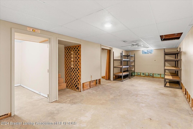 basement with a paneled ceiling and ceiling fan