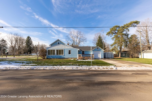 view of front of home featuring a porch, a garage, a storage shed, and a front lawn