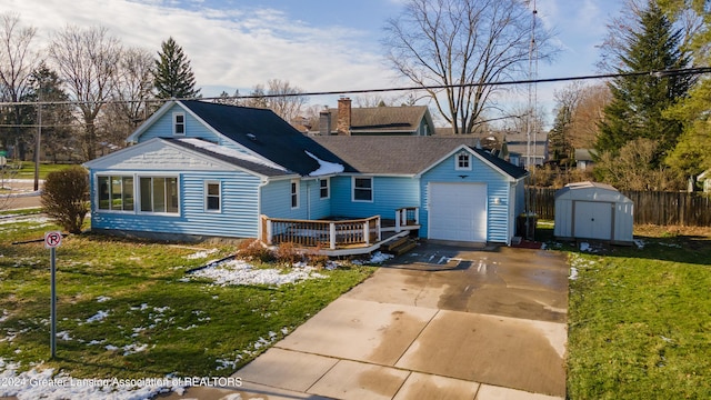 rear view of property featuring a shed, a garage, a deck, and a lawn