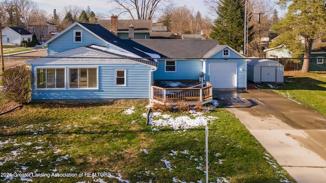 back of property featuring a lawn, a wooden deck, a garage, and a storage unit