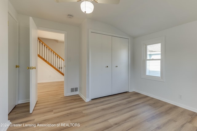 unfurnished bedroom with light wood-type flooring, a closet, lofted ceiling, and ceiling fan