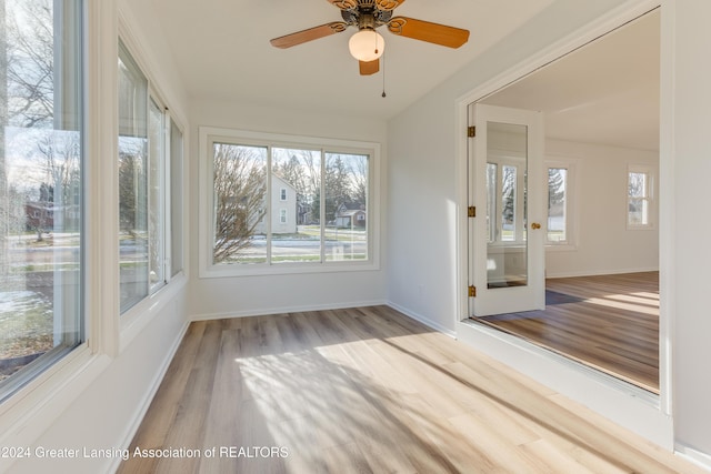 unfurnished sunroom featuring ceiling fan and a wealth of natural light