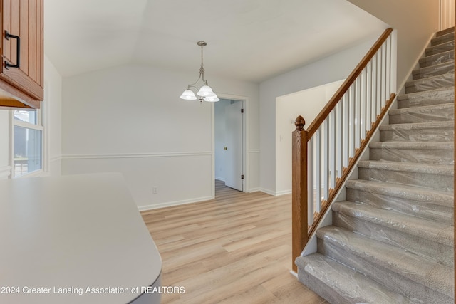 stairs with hardwood / wood-style flooring, lofted ceiling, and a chandelier