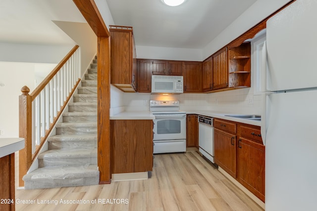 kitchen with decorative backsplash, white appliances, and light hardwood / wood-style flooring