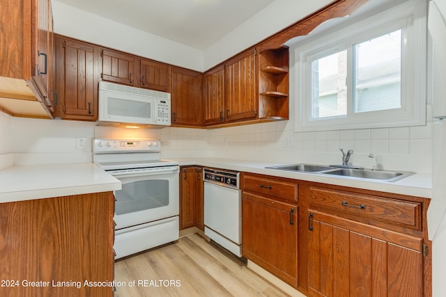 kitchen featuring backsplash, white appliances, sink, and light hardwood / wood-style flooring