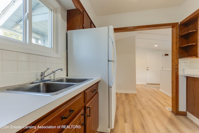 kitchen with backsplash, sink, white refrigerator, vaulted ceiling with beams, and light hardwood / wood-style floors