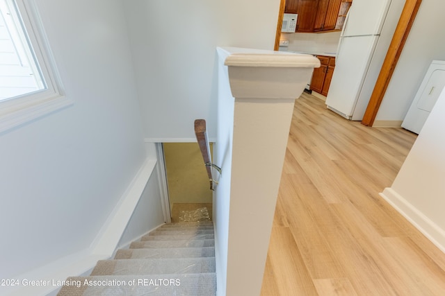 staircase with hardwood / wood-style floors and washer / dryer