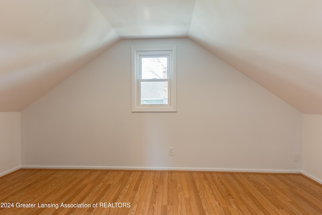 bonus room with light wood-type flooring and vaulted ceiling