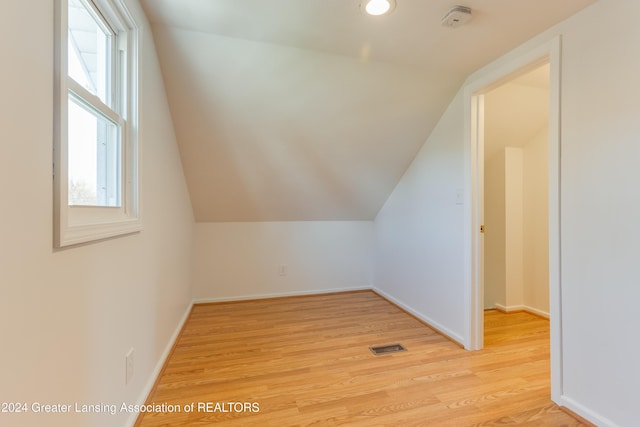 additional living space featuring light hardwood / wood-style floors, vaulted ceiling, and a wealth of natural light