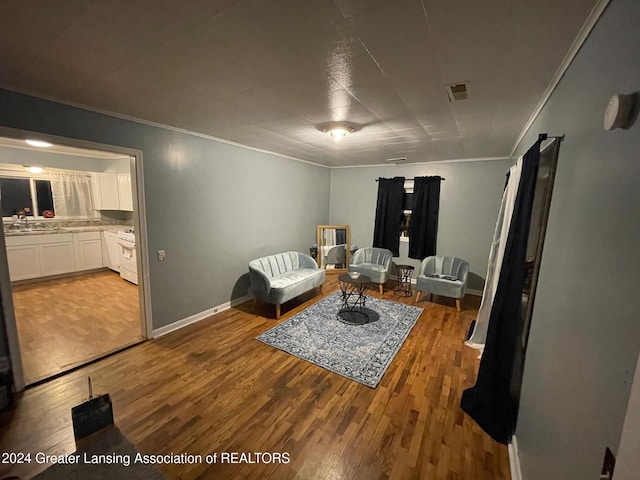 living room featuring hardwood / wood-style flooring, crown molding, and sink