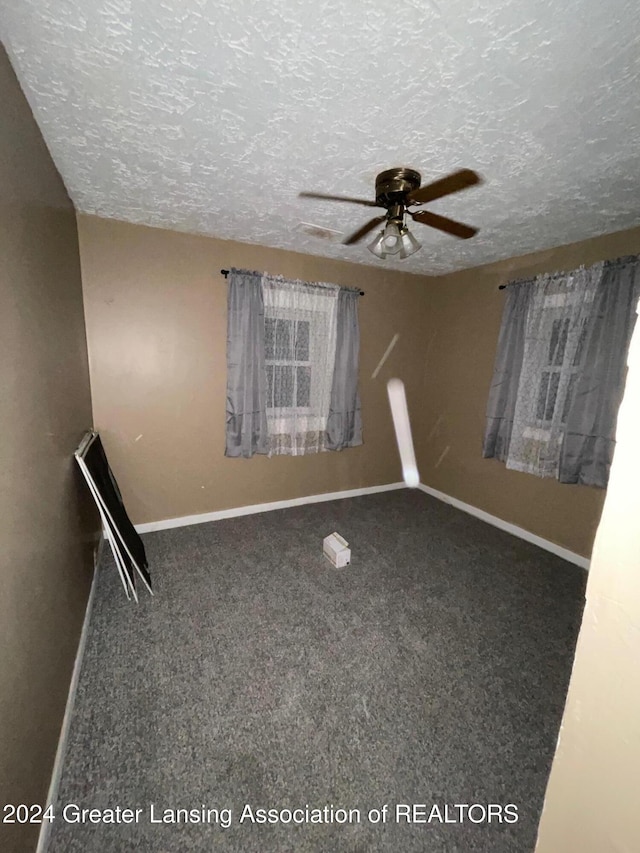 carpeted spare room featuring ceiling fan and a textured ceiling