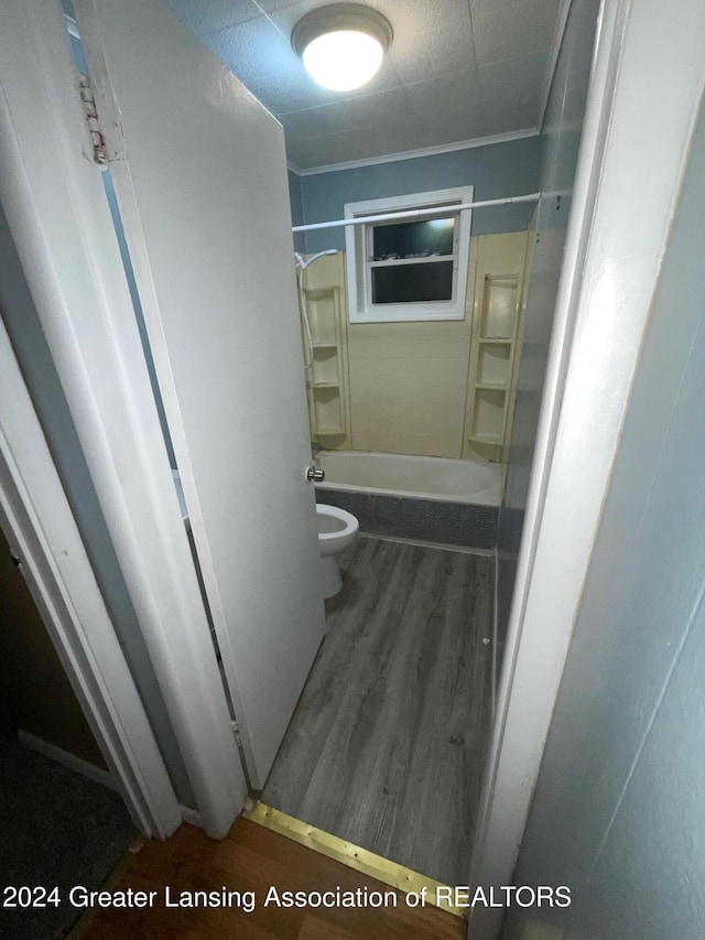 bathroom featuring hardwood / wood-style floors, toilet, crown molding, and bathing tub / shower combination