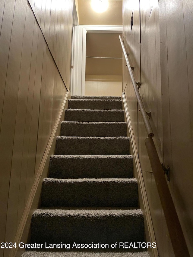 stairway featuring wooden walls