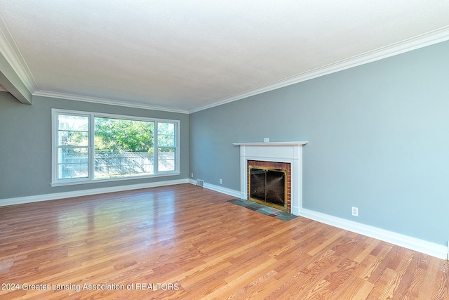 unfurnished living room with a brick fireplace, ornamental molding, and light hardwood / wood-style floors