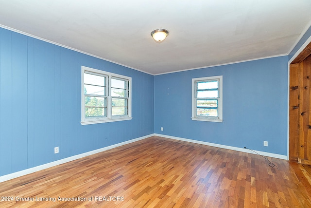 spare room featuring crown molding, wooden walls, and hardwood / wood-style floors