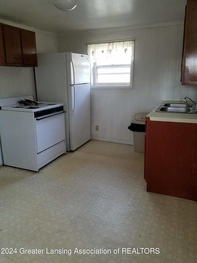 kitchen featuring white range oven, wood walls, and sink