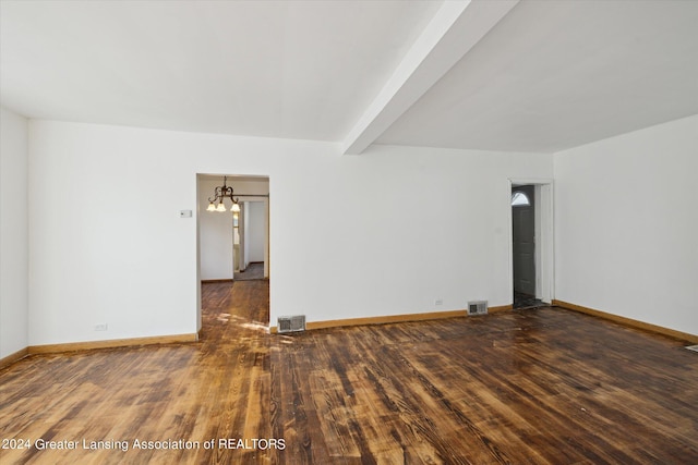 empty room featuring beam ceiling, dark wood-type flooring, and a chandelier