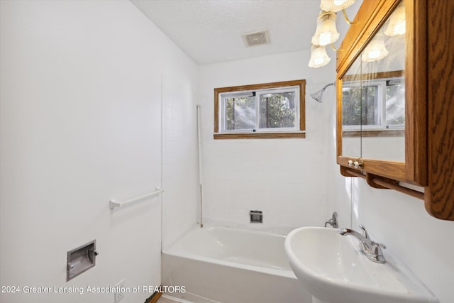 bathroom featuring tiled shower / bath, a textured ceiling, and sink