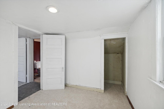 unfurnished bedroom with a closet and light colored carpet