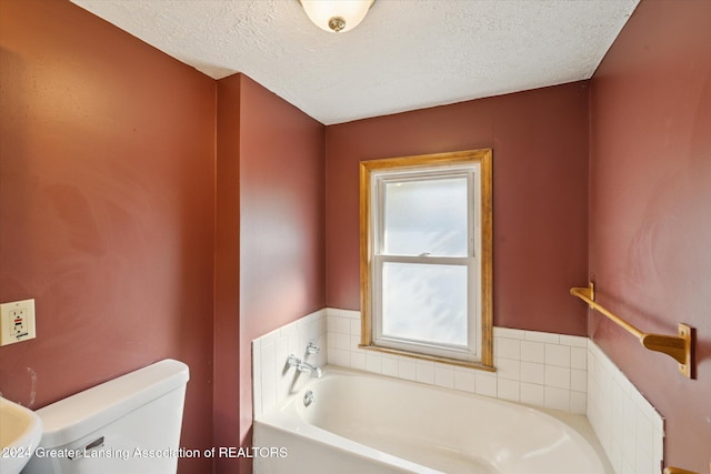 bathroom featuring a textured ceiling, a tub to relax in, and toilet