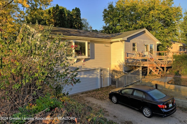 ranch-style house with stairs, driveway, a wooden deck, and an attached garage