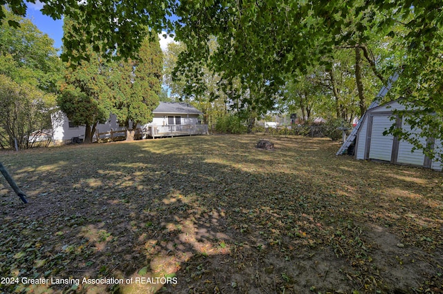 view of yard featuring an outbuilding, a wooden deck, and a storage unit
