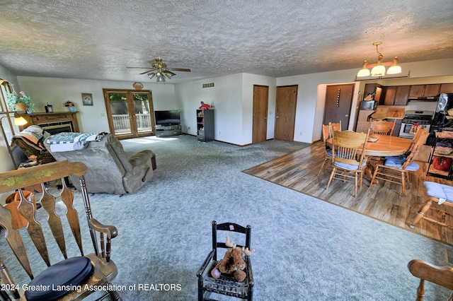 carpeted living area with visible vents, a ceiling fan, a fireplace, and a textured ceiling