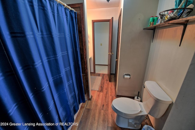 full bath with toilet, curtained shower, and wood finished floors