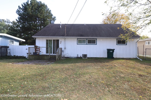 rear view of house featuring central AC unit and a lawn