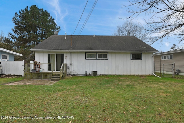 back of property with central AC unit and a yard