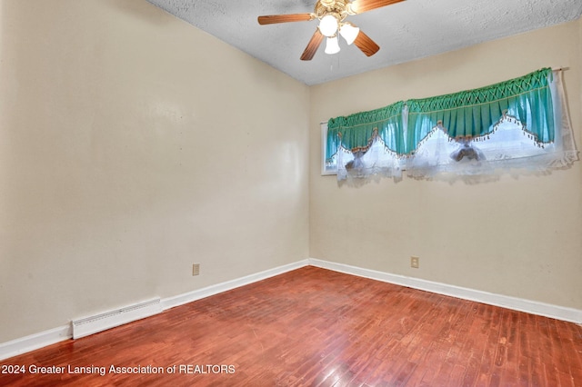 empty room featuring a textured ceiling, hardwood / wood-style flooring, ceiling fan, and a baseboard heating unit