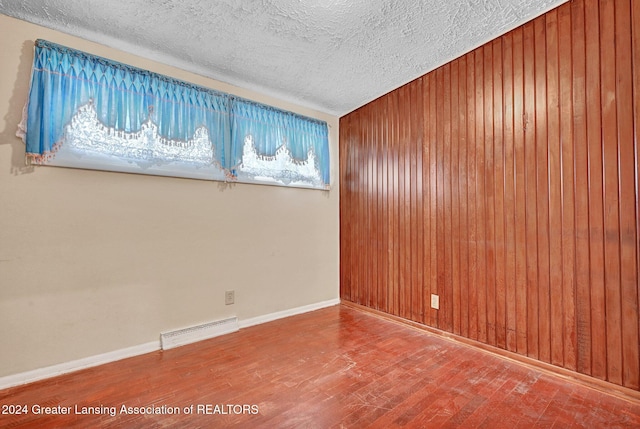 empty room with a textured ceiling and hardwood / wood-style flooring