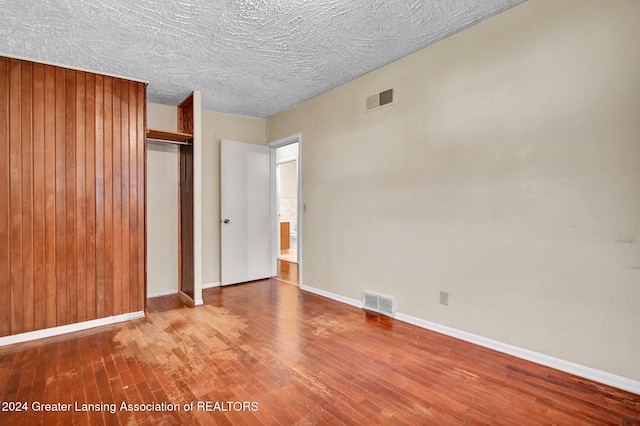 unfurnished bedroom with wood-type flooring, a textured ceiling, and a closet