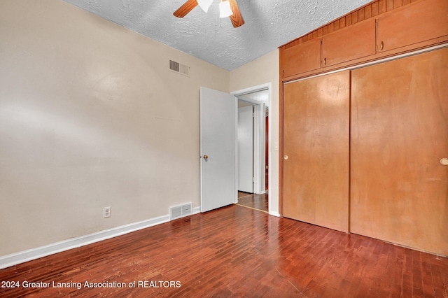 unfurnished bedroom with vaulted ceiling, a textured ceiling, dark hardwood / wood-style floors, ceiling fan, and a closet