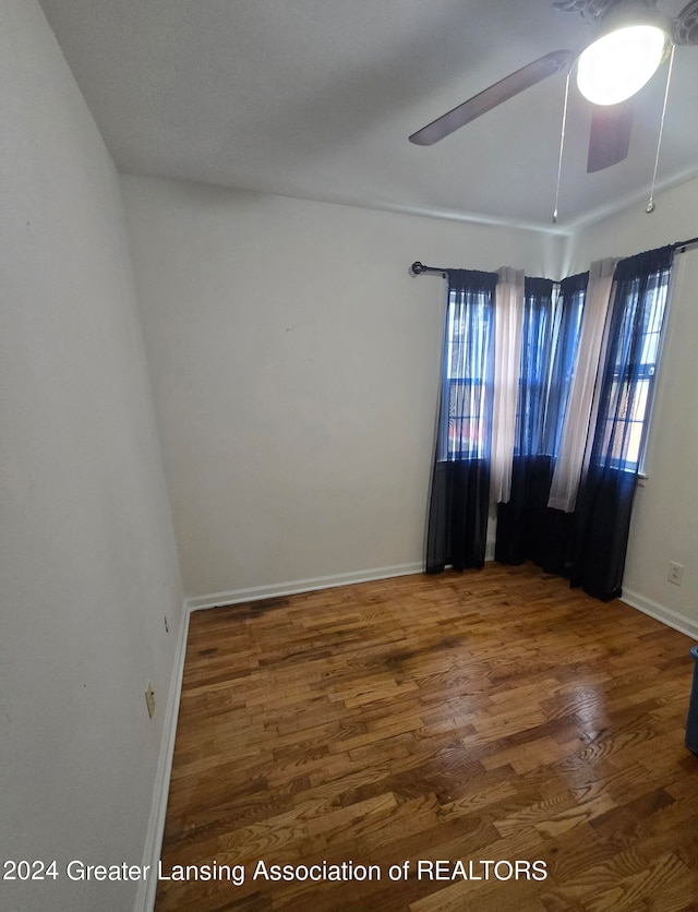 spare room with ceiling fan, plenty of natural light, and dark wood-type flooring