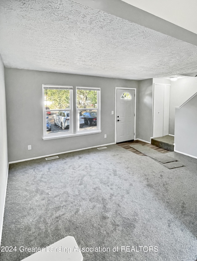 unfurnished living room featuring carpet flooring and a textured ceiling