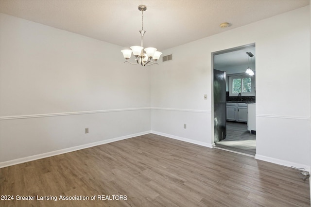 empty room featuring hardwood / wood-style flooring, a chandelier, and sink