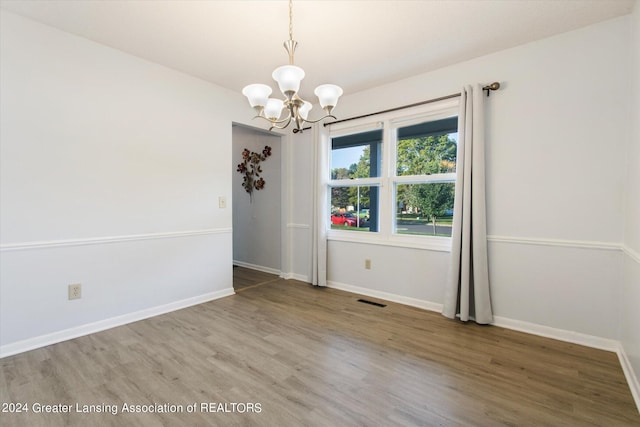 spare room with hardwood / wood-style flooring and a notable chandelier