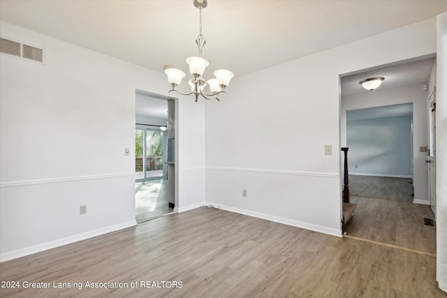 spare room with wood-type flooring and a notable chandelier