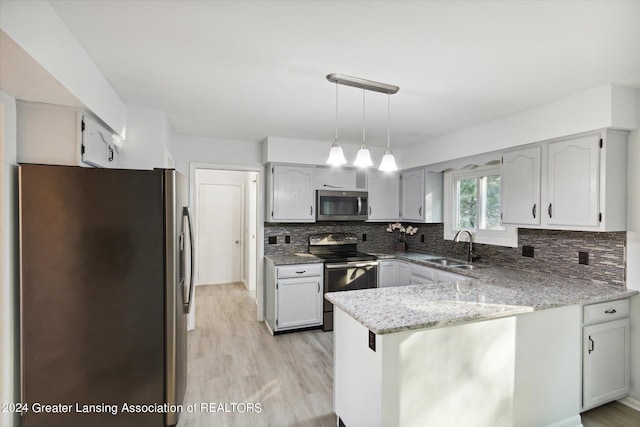 kitchen with decorative backsplash, light wood-type flooring, pendant lighting, stainless steel appliances, and kitchen peninsula