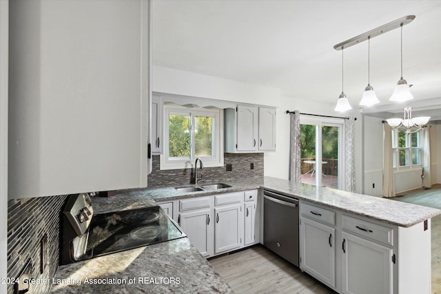 kitchen featuring plenty of natural light, black range oven, sink, dishwasher, and kitchen peninsula