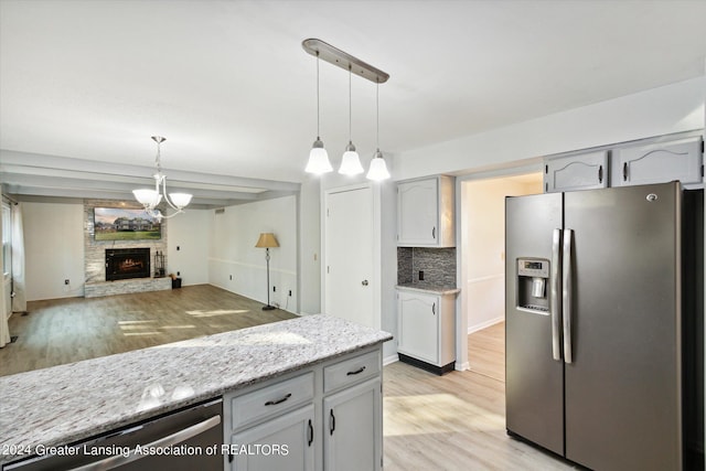 kitchen featuring decorative light fixtures, stainless steel appliances, backsplash, and light hardwood / wood-style floors