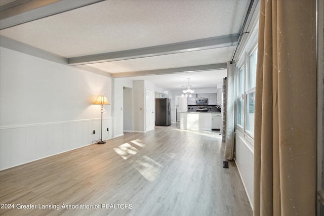 unfurnished living room with beamed ceiling, a chandelier, light hardwood / wood-style floors, and a textured ceiling